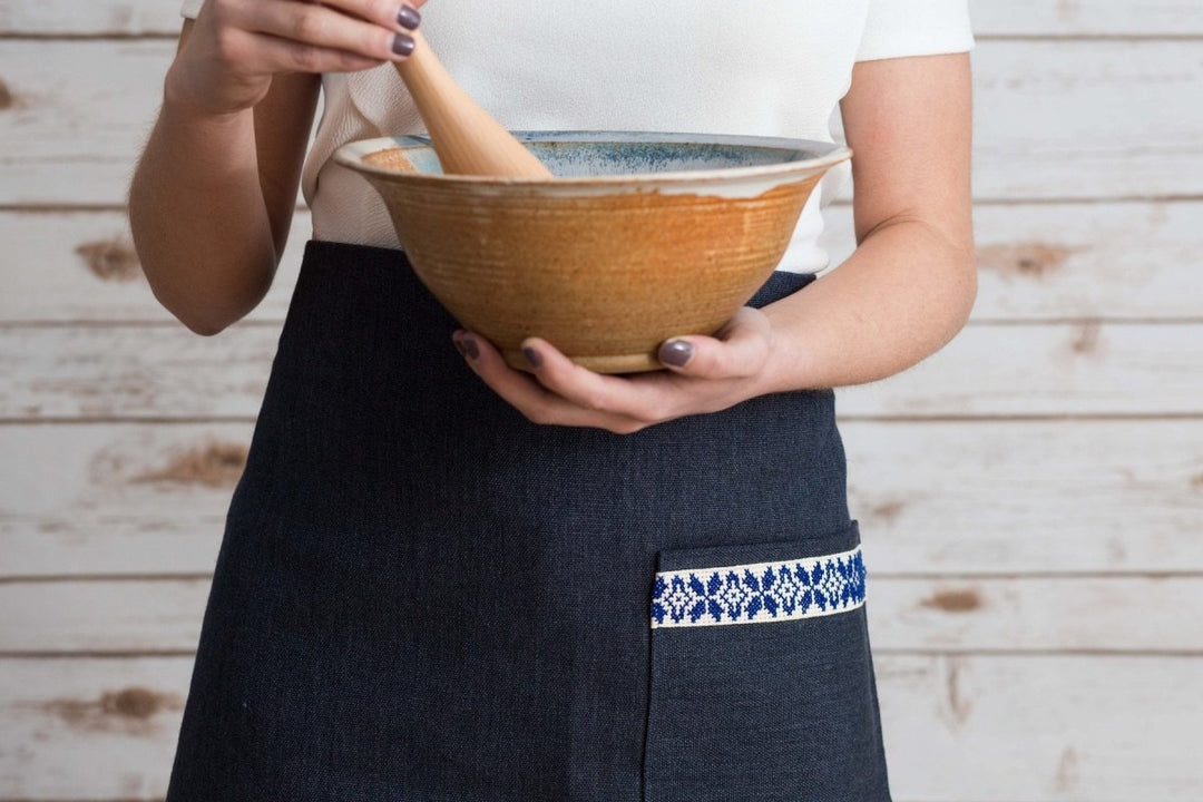 Navy half apron with waist ties and a blue-and-white embroidered tatreez band.