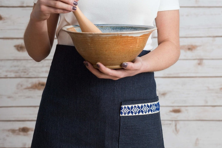 Navy half apron with waist ties and a blue-and-white embroidered tatreez band.
