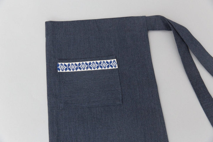 Hand-embroidered navy waist apron with a blue-and-white Sea motif band, made in Palestine.