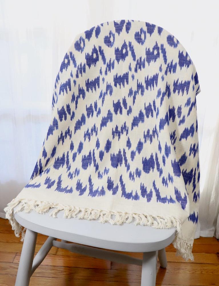 Handwoven cotton throw in a blue ikat pattern, soft texture.