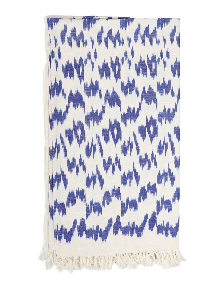 Handwoven cotton throw in a blue ikat pattern on an off-white base.