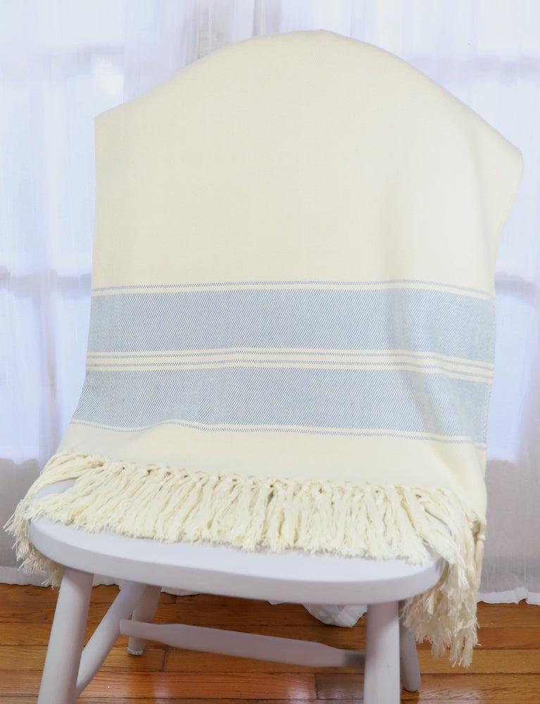 Handwoven cotton throw with blue stripes, soft fabric.