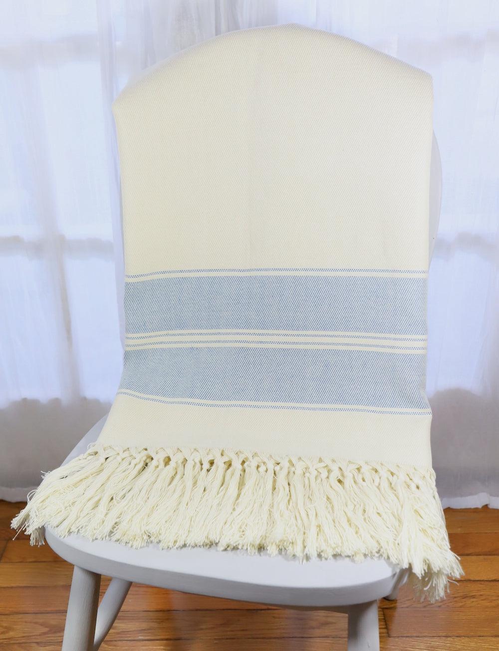 Handwoven cotton throw with blue stripes on an off-white base.