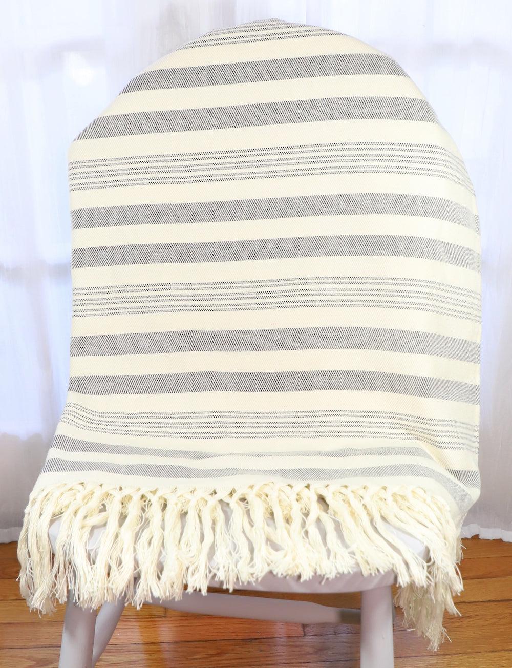 Handwoven cotton throw with charcoal stripes, draped.