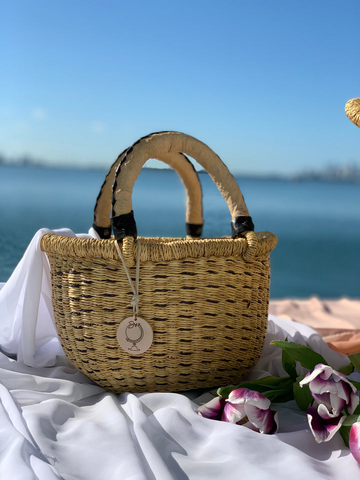 The Petite Victoria handwoven straw basket bag, showing its intricate weave and natural finish.